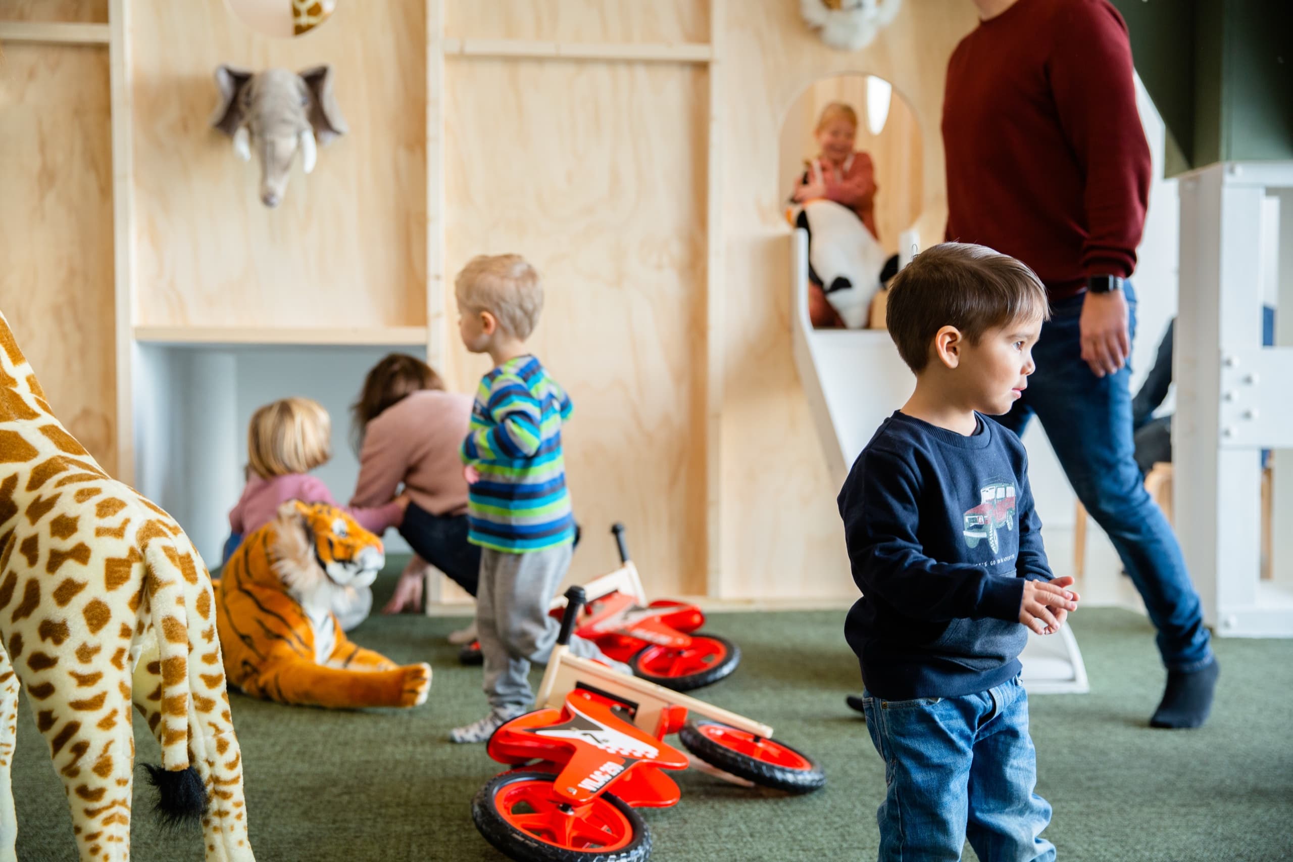 Barn leker med balansesykler og tøydyr i lekerommet